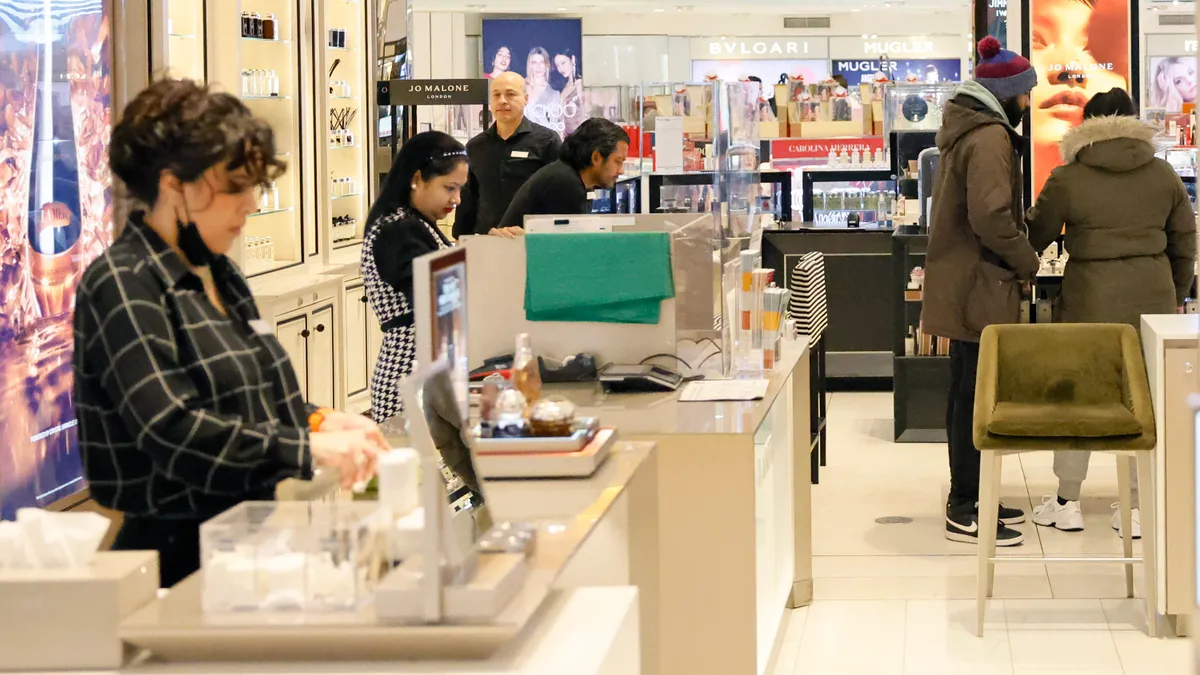 Employees work at a retail checkout counter.