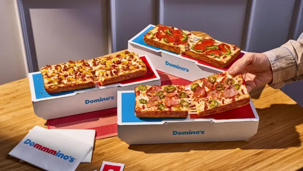 Three rectangular pizzas with Domino's brand packaging.