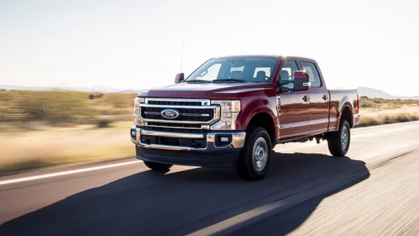 A red 2020 Ford F-250 Lariat Ultimate driving on a road.