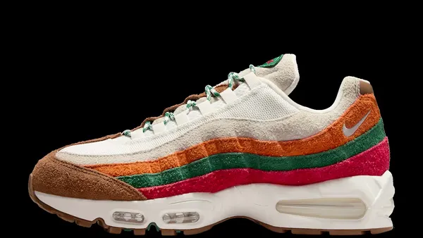 A photo of a white, brown, orange, green and red sneaker in side profile against a black background with the nike logo on the orange stripe near the ankle.