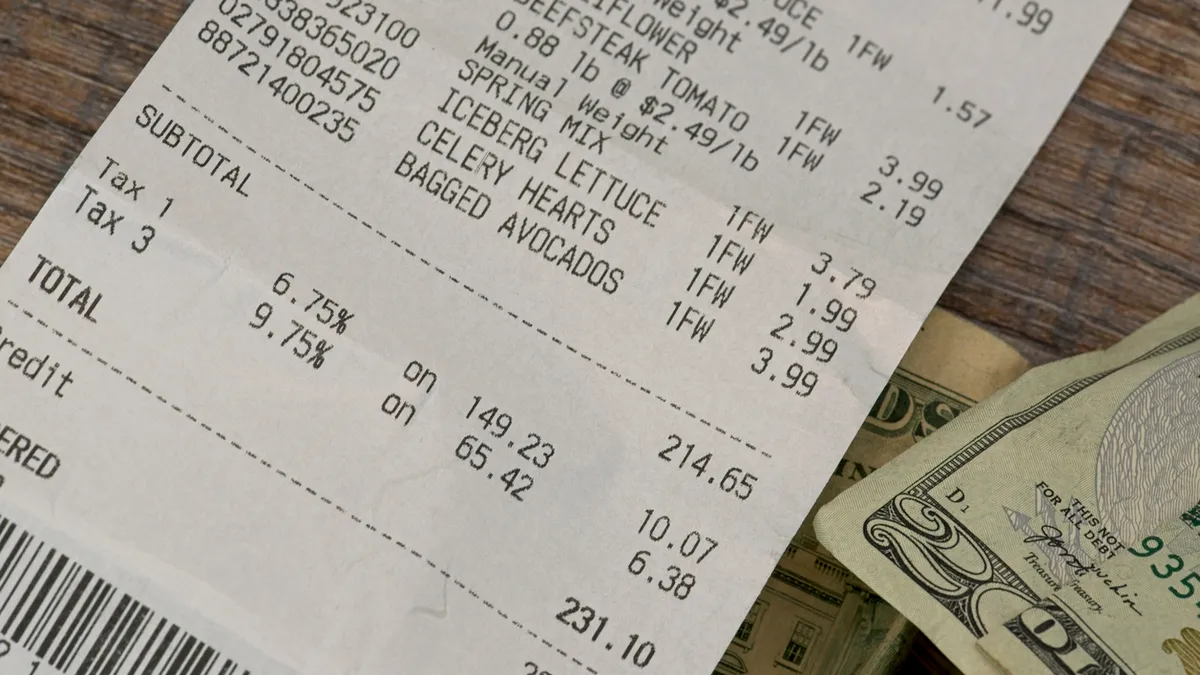 Grocery receipt with cash on a wood background