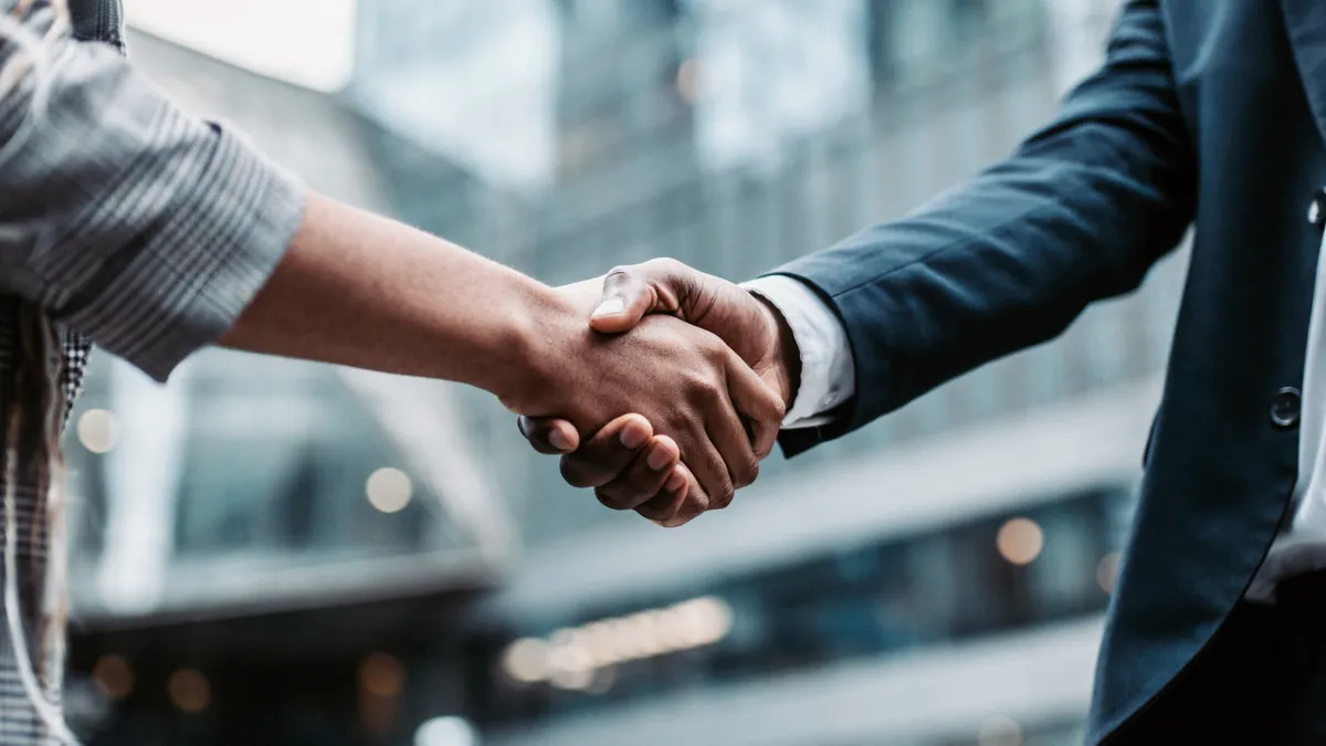 Two people shake hands.