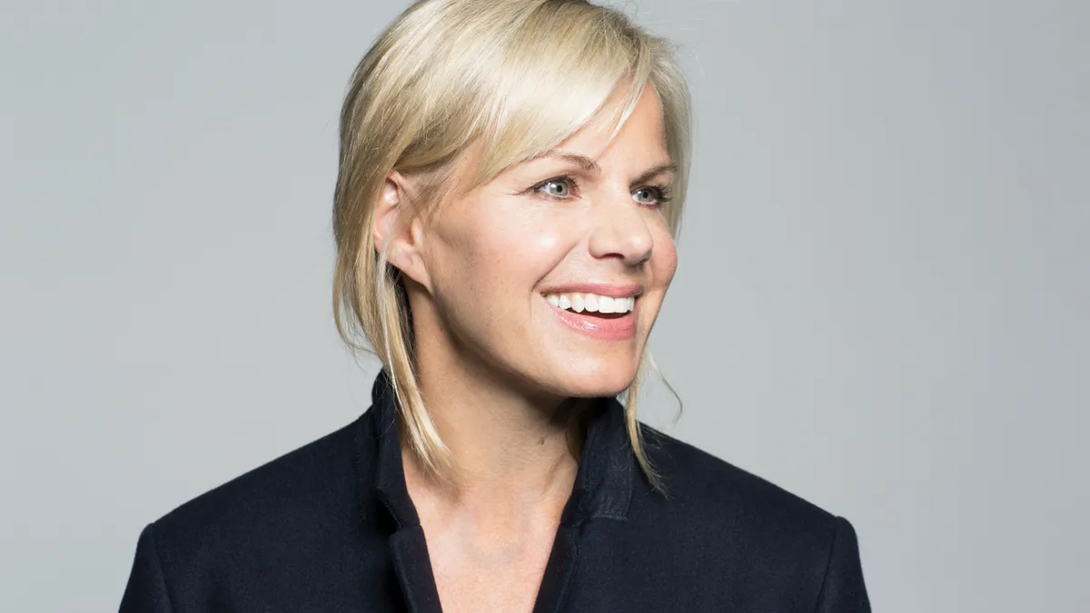 A headshot of Gretchen Carlson wearing a navy blazer, looking off to the side