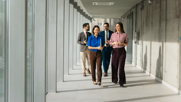Business professionals walking through modern office hallway
