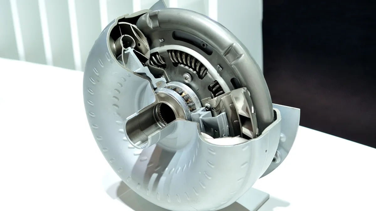 A silver torque converter with an a section cut to show its internal parts.