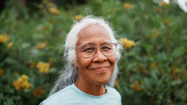 A white-haired person of Hawaiian and Chinese descent smiles at the camera.
