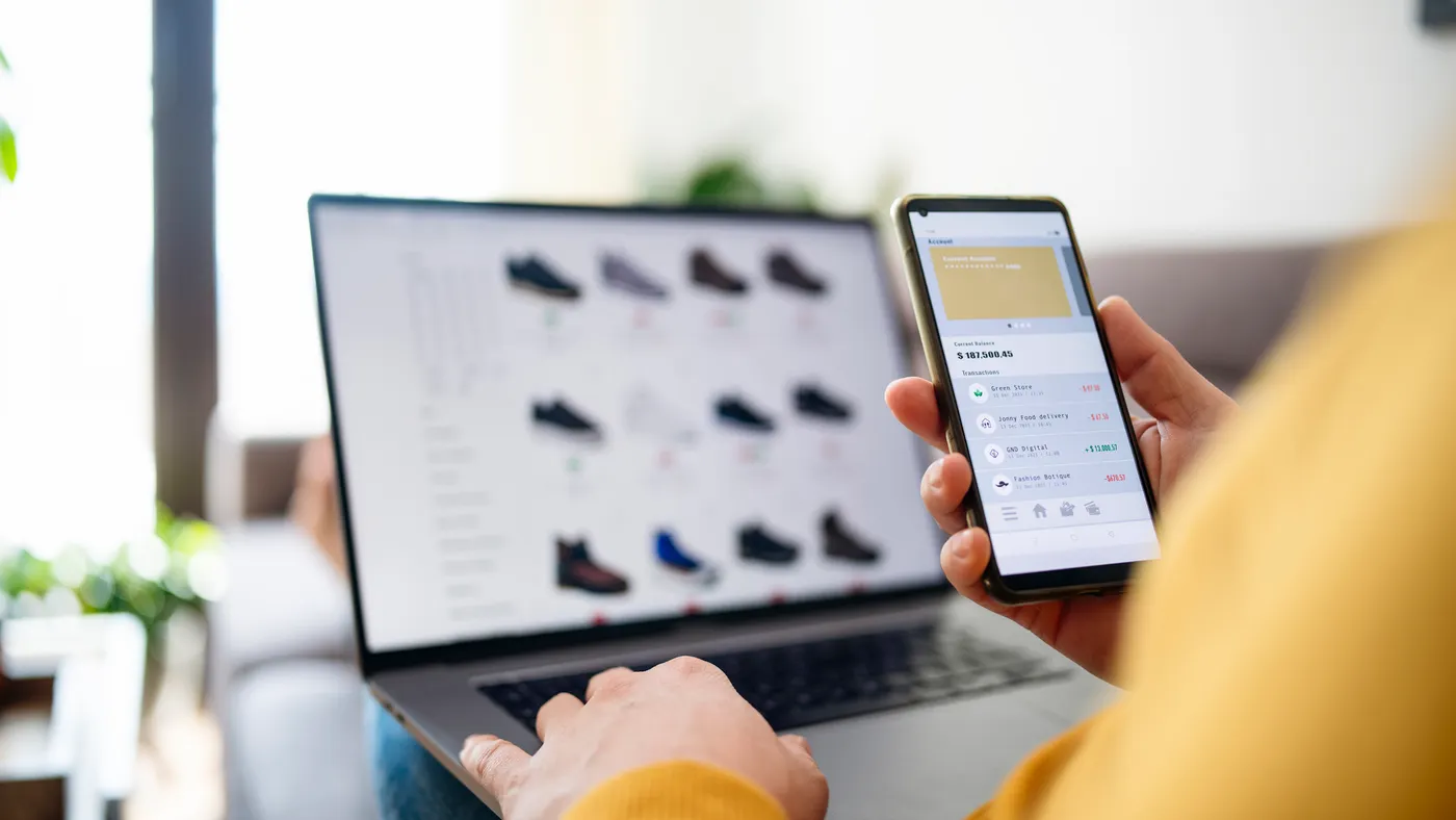A person shops online on a laptop and phone.