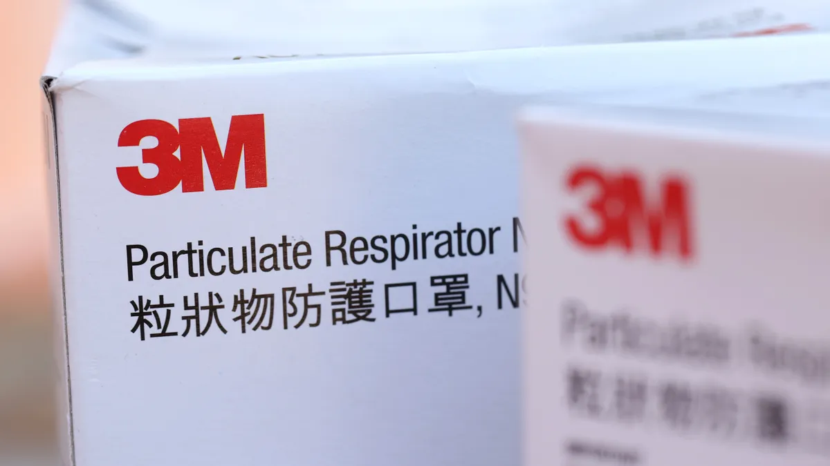 White boxes of 3M brand N95 particulate respirators are displayed on a table.