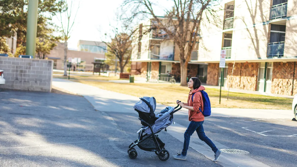 A person pushes a baby stroller across a parking lot.