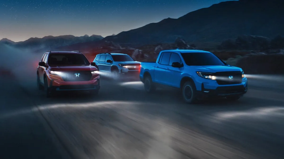 Three Honda cars with headlights on traveling on a dark road.