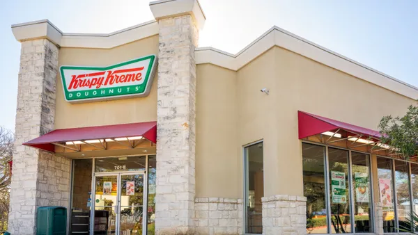 A biege building with signage in red and green that says Krispy Kreme Doughnuts
