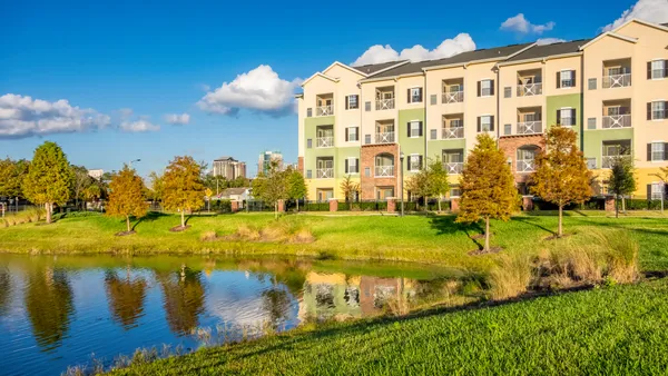 A mid-rise apartment building behind a lake.