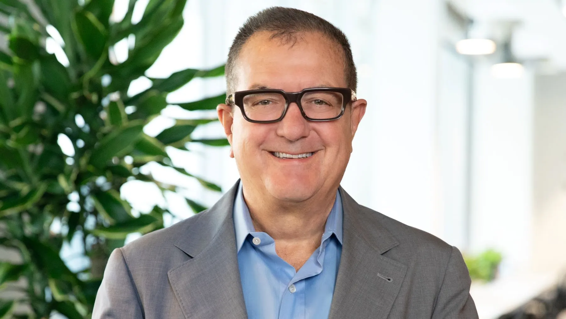 A person in a gray business suit stands for a photograph.