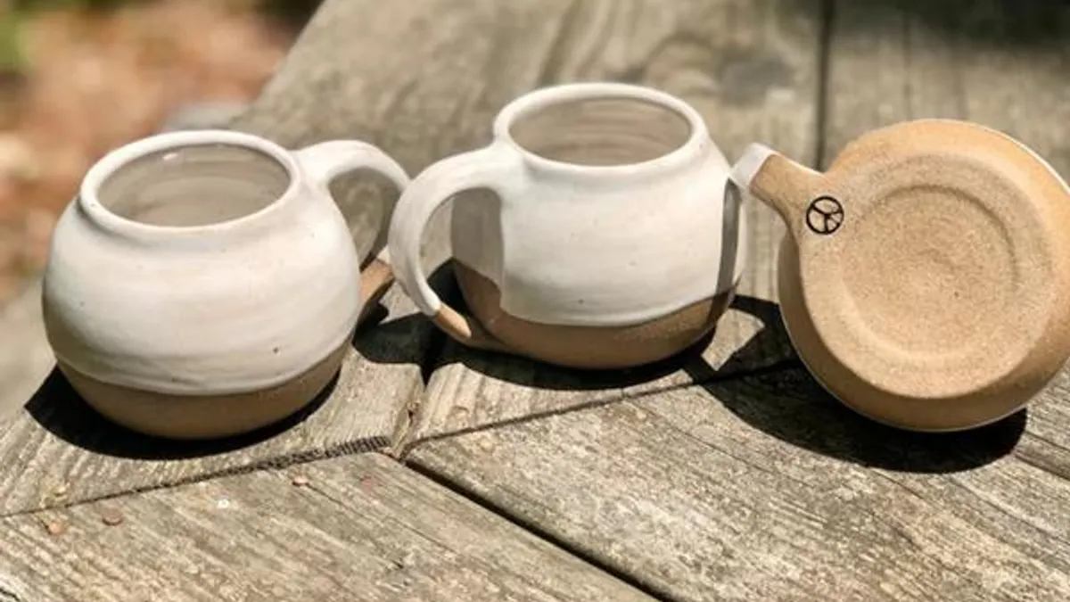 Three handmade, glazed coffee mugs displayed on a table