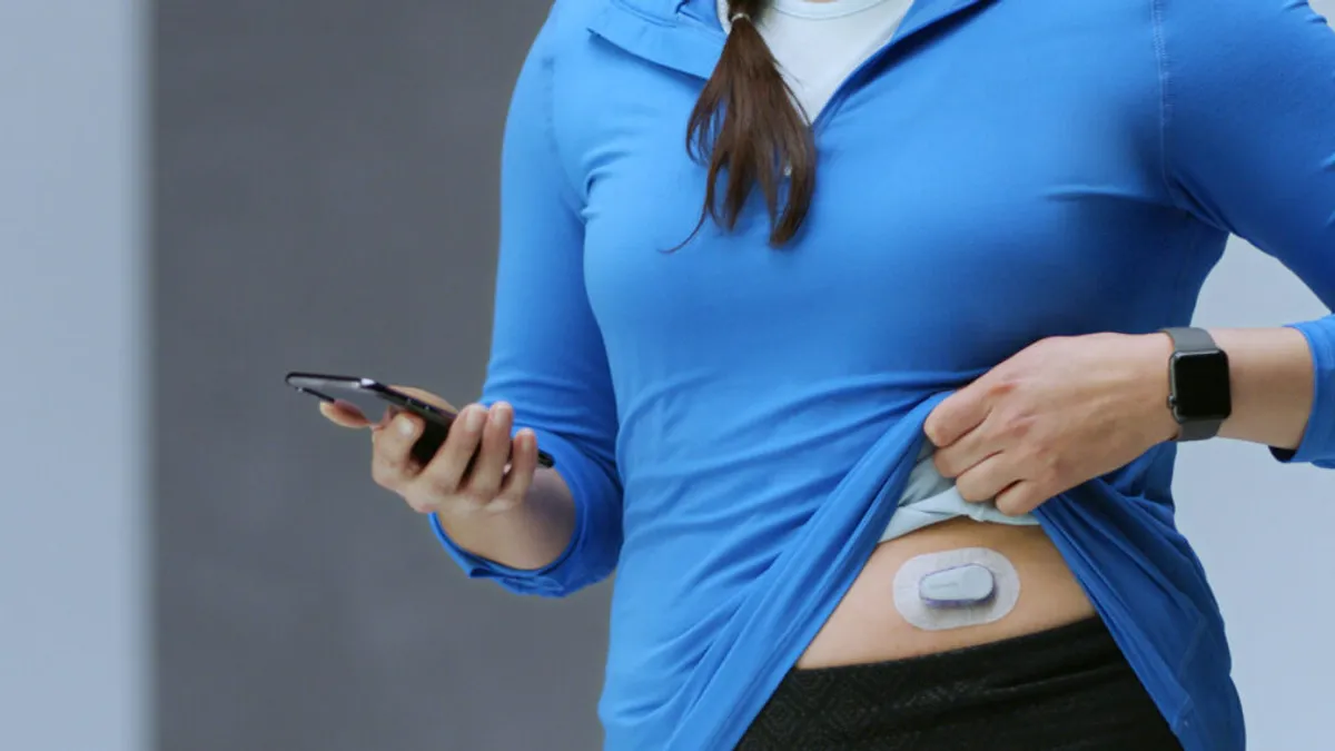 A woman lifting her shirt to expose her midriff and show a Verily Onduo CGM