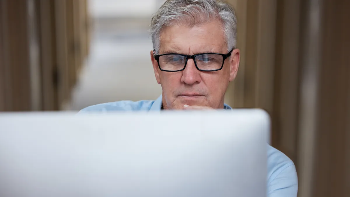 Shot of a mature businessman sitting alone in the office and using his computer