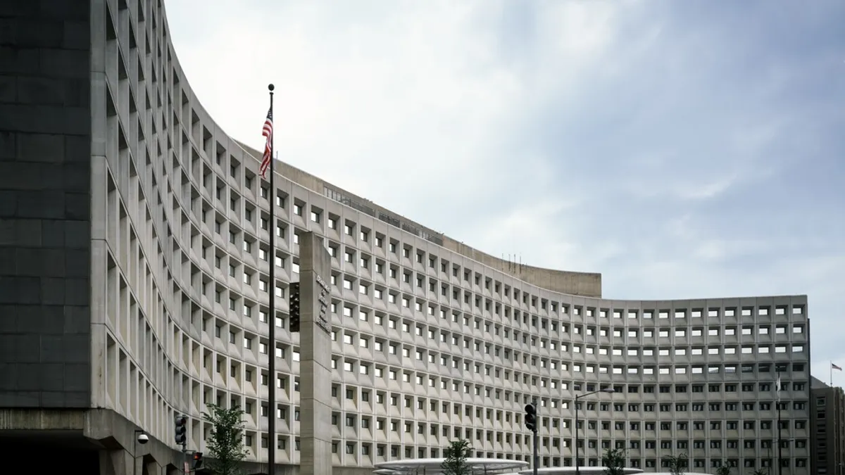 A curved beige building with rows of square windows.