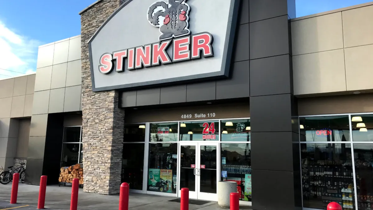 A photo of the exterior of a convenience store. A sign over the door has a picture of a cartoon skunk over the word "Stinker."