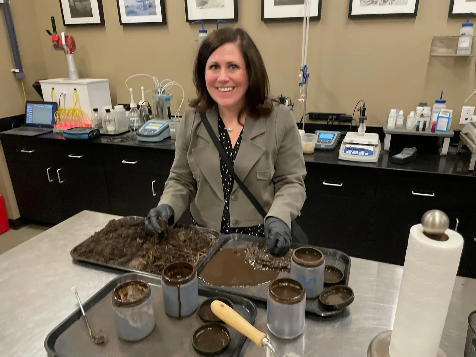 A woman with gloves handles anaerobic digester material