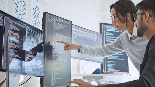 Woman pointing at screen with code.