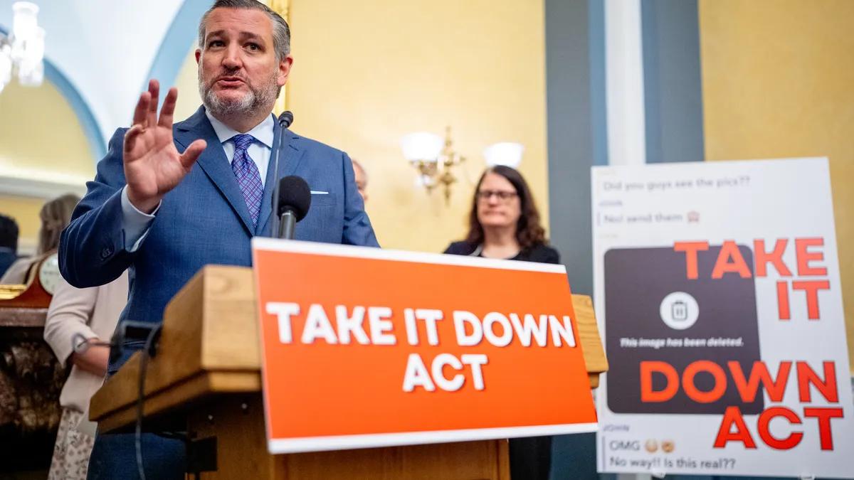 Sen. Ted Cruz stands at a podium with an orange sign that reads "Take It Down Act" in front of another sign with the same language.