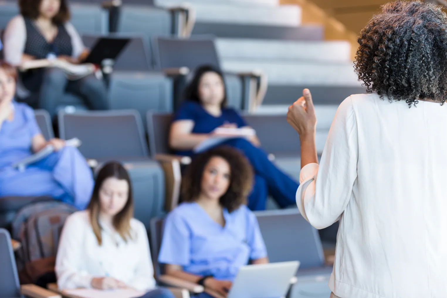 A college professor lectures to a room full of students.