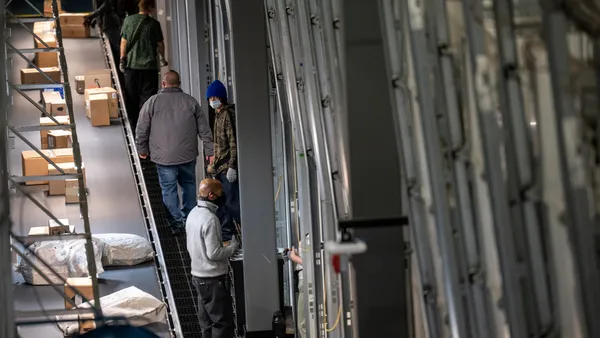 UPS package handlers move shipments from a conveyor belt into package cars at the UPS Centennial Ground Hub on December 6, 2021 in Louisville, Kentucky.