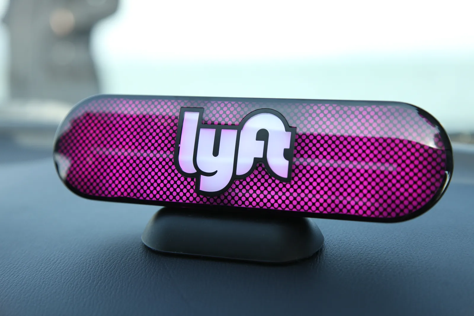 A photo of a Lyft logo on a car's dashboard.