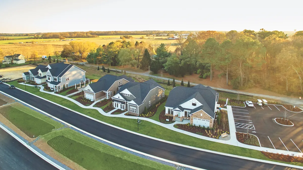 Aerial picture of single-family homes next to a street with trees in the background.