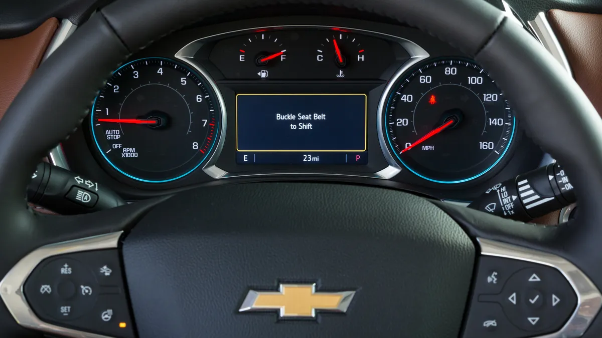 The instrument cluster of a GM vehicle showing a message "Buckle seat belt to shift."