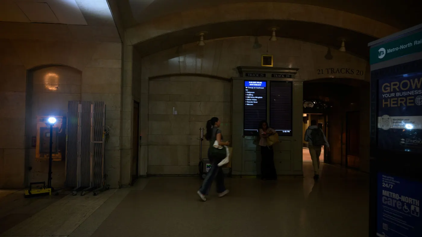People walk through an area illuminated by a portable floor light in Grand Central Terminal following a power outage.