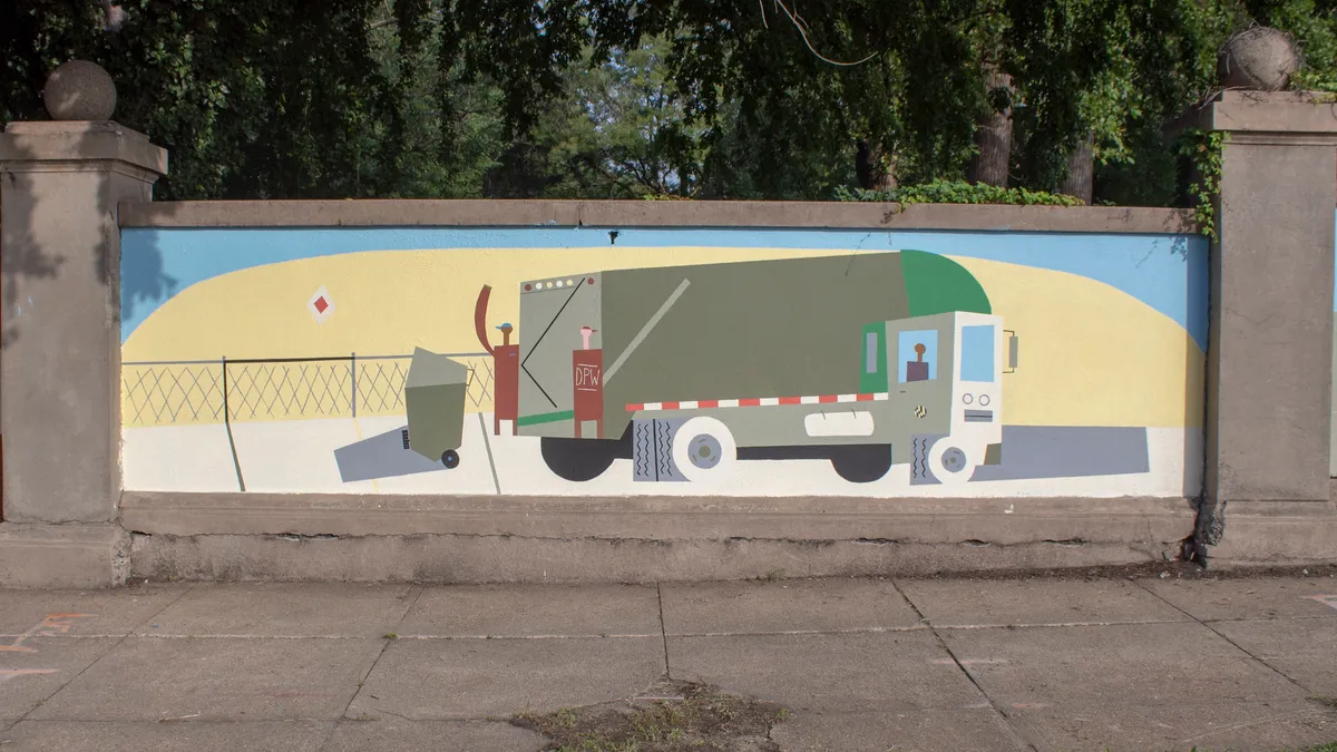 Lively mural on stone wall depicting waste collection workers on a truck