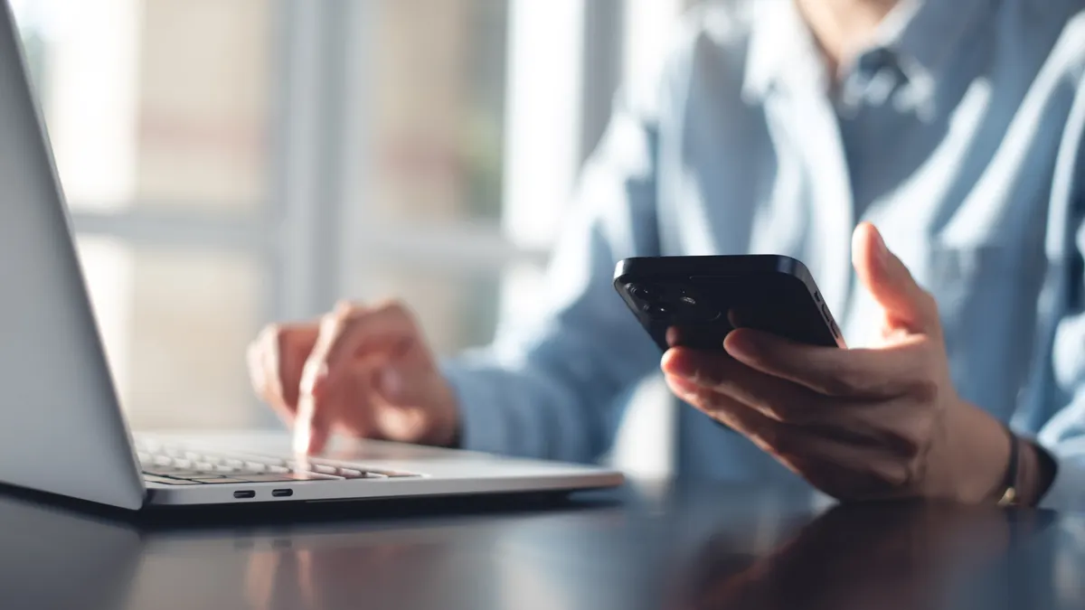 Business person using mobile smart phone and computer.