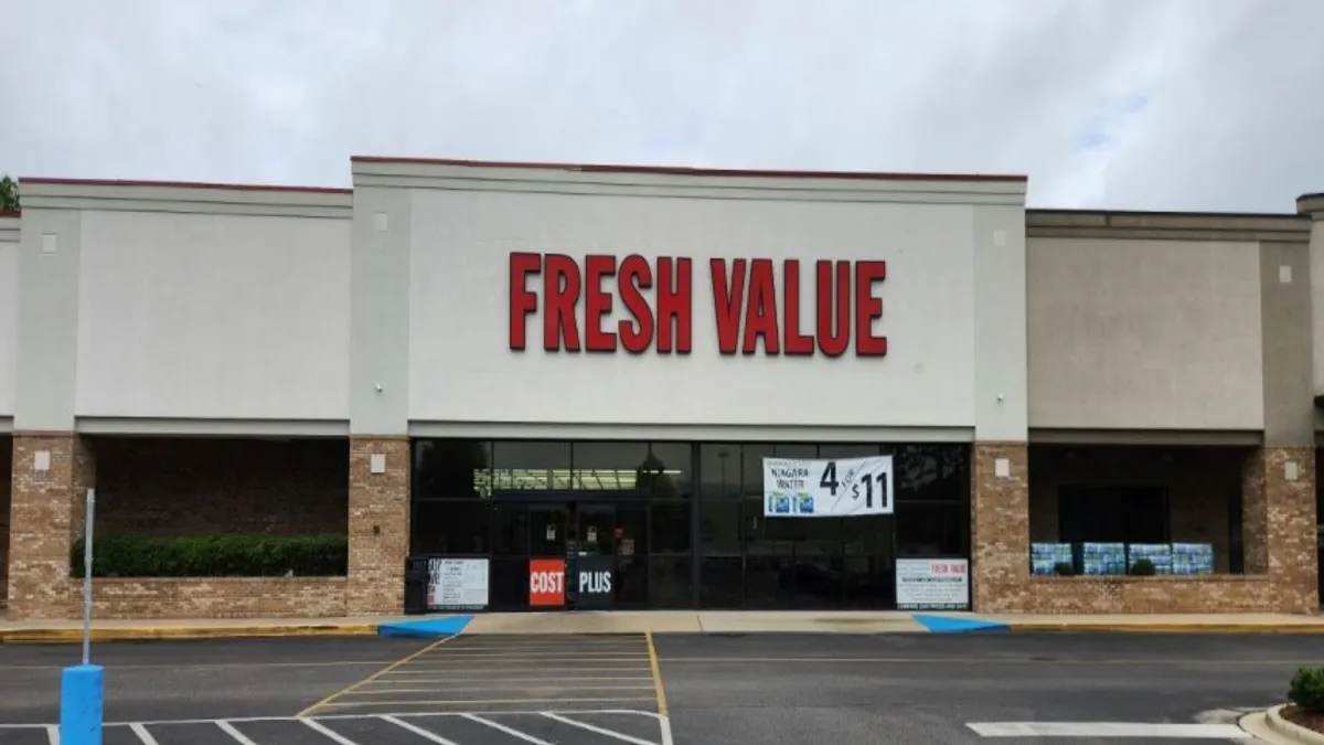 Exterior a supermarket with the words "Fresh Value" in red above the entrance.