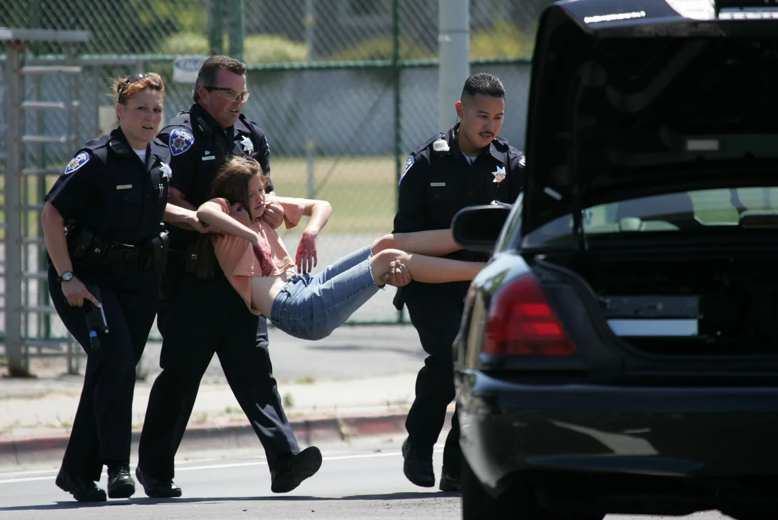 Three policeman carry a student