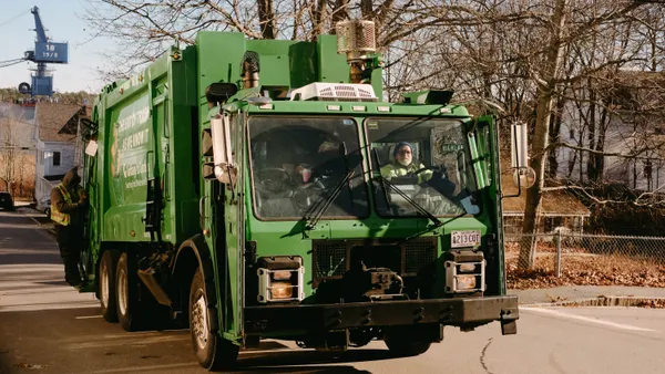 A Garbage to Garden collection truck drives down the street with a crane in the background