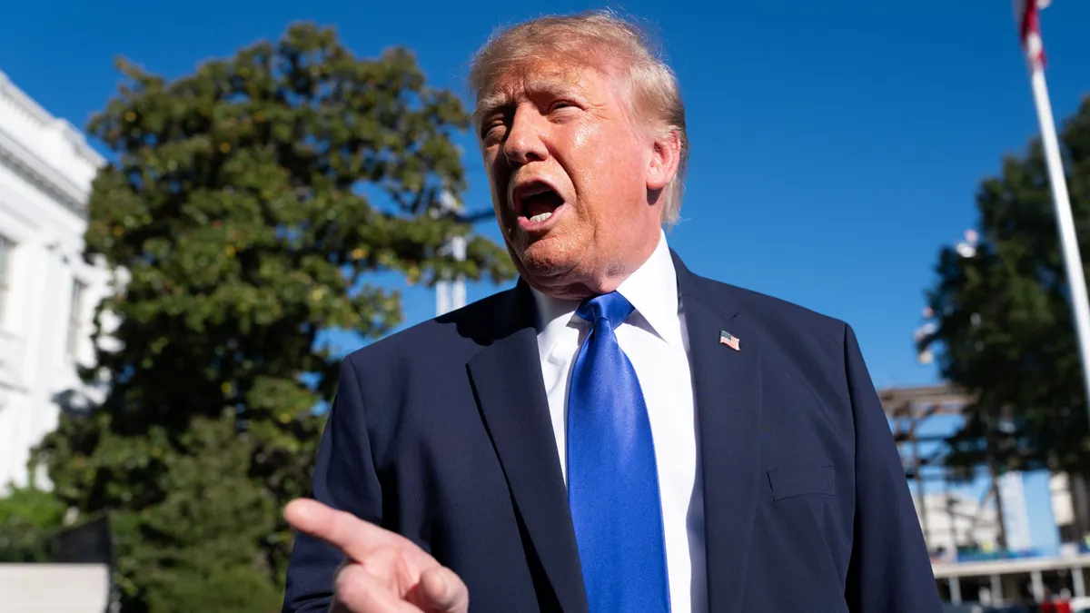 President Donald Trump points with his right hand while speaking with reporters outside the White House.