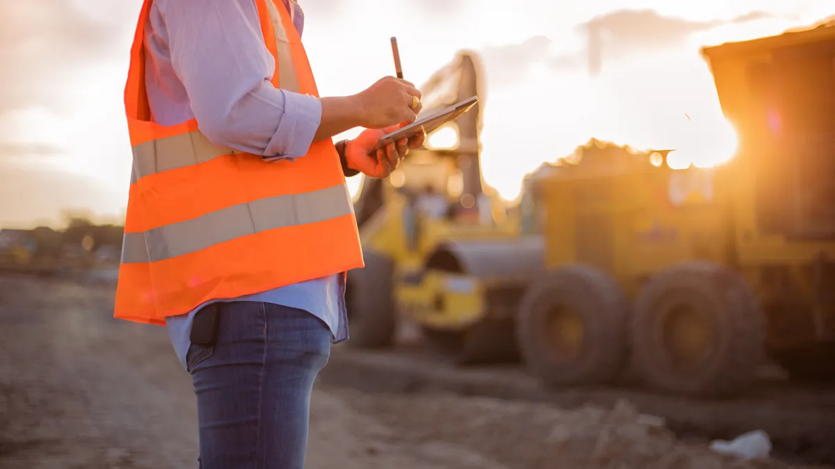 engineer with hardhat using tablet pc computer inspecting and working at construction site