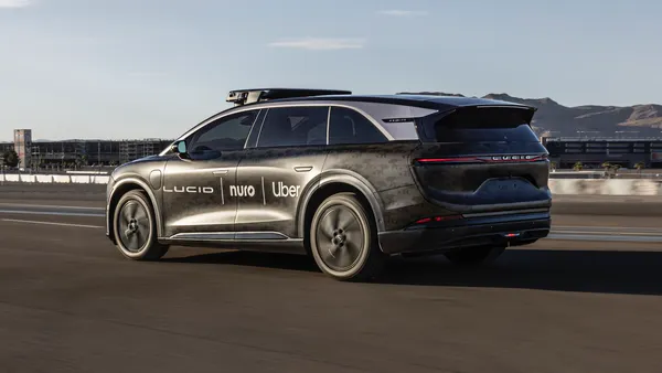 Lucid Gravity robotaxi equipped with roff-mounted sensors and the logos of Uber, Nuro and Lucid on the side doors.