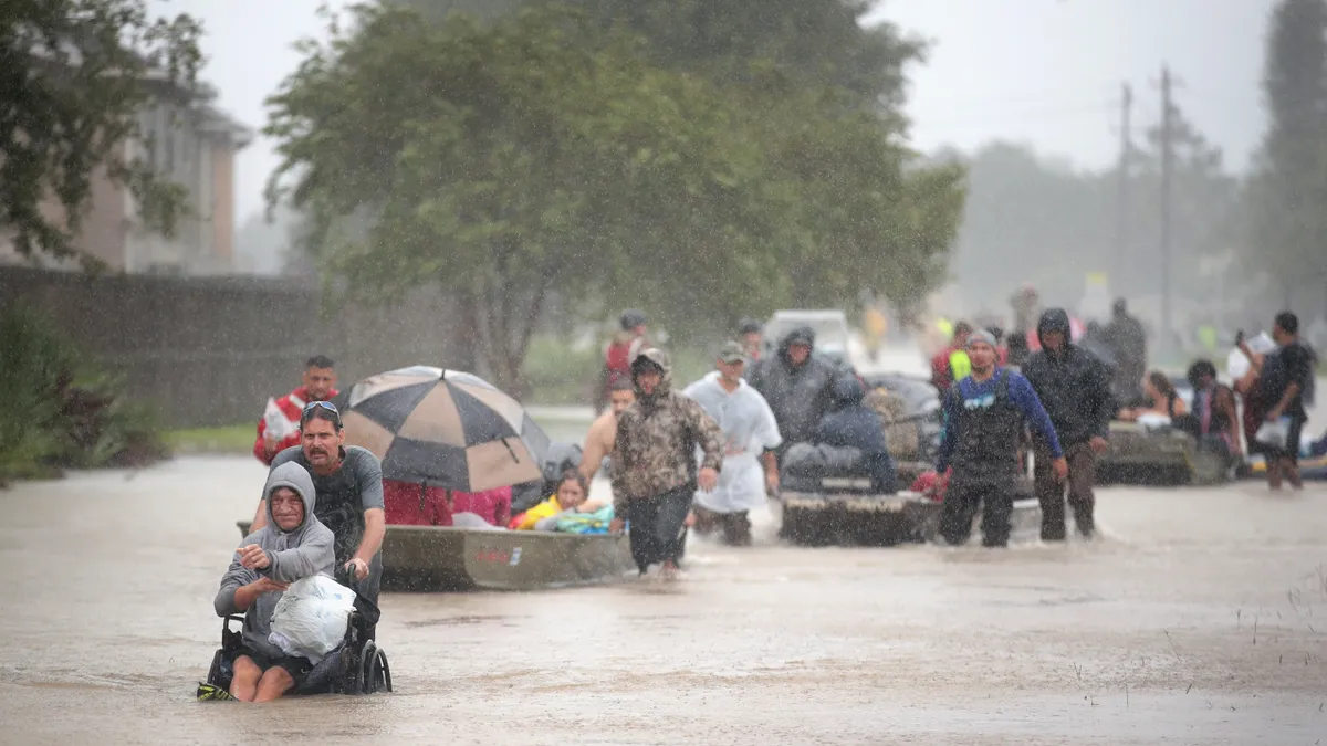 People walks through flooded street with boats