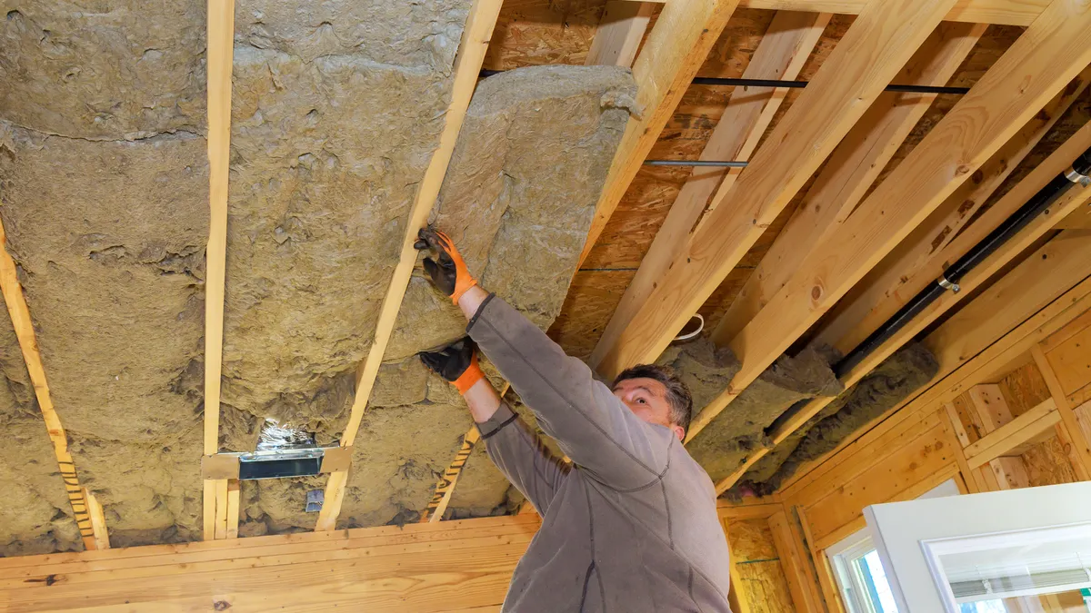 A man puts insulation into a ceiling.