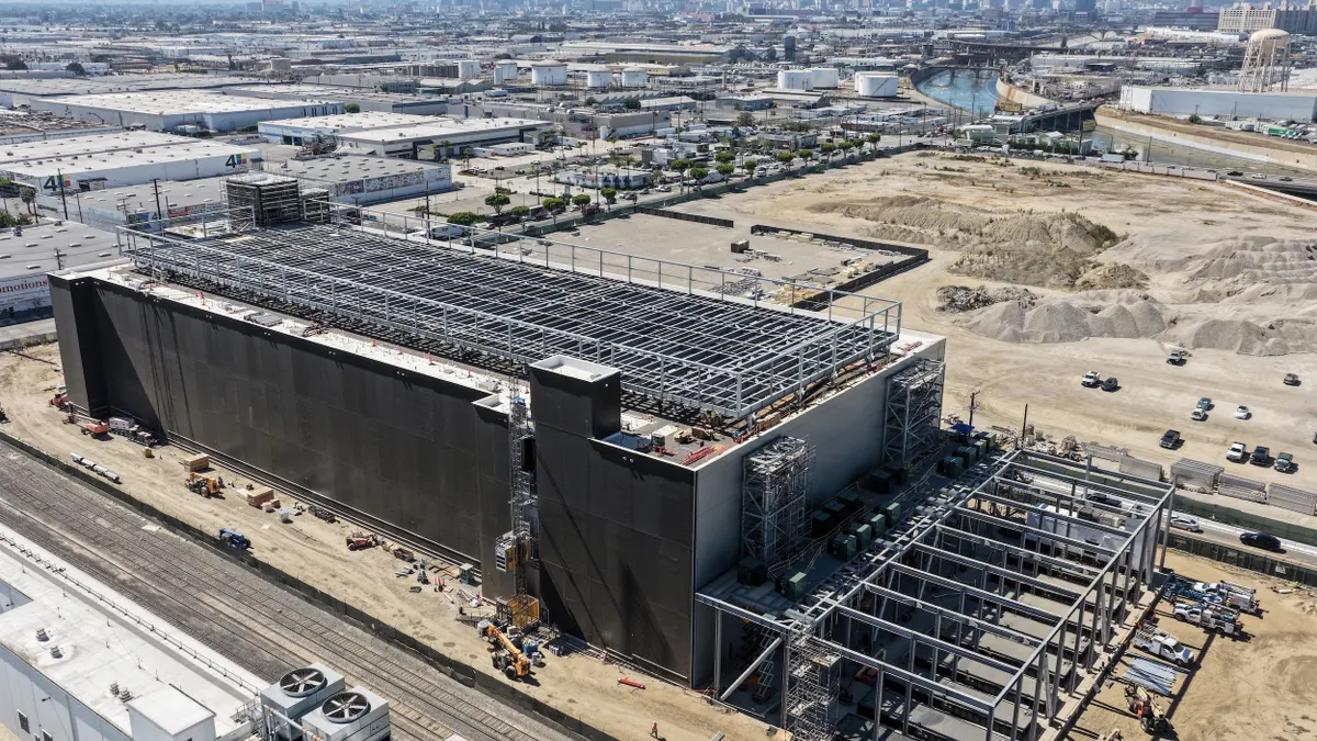Aerial view of a building under construction with city skyline in the background.