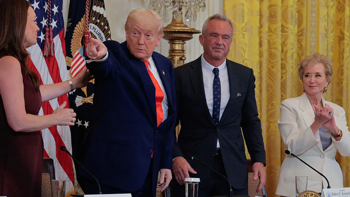 Four people are standing in a room behind a table. One person is pointing while the others are clapping.