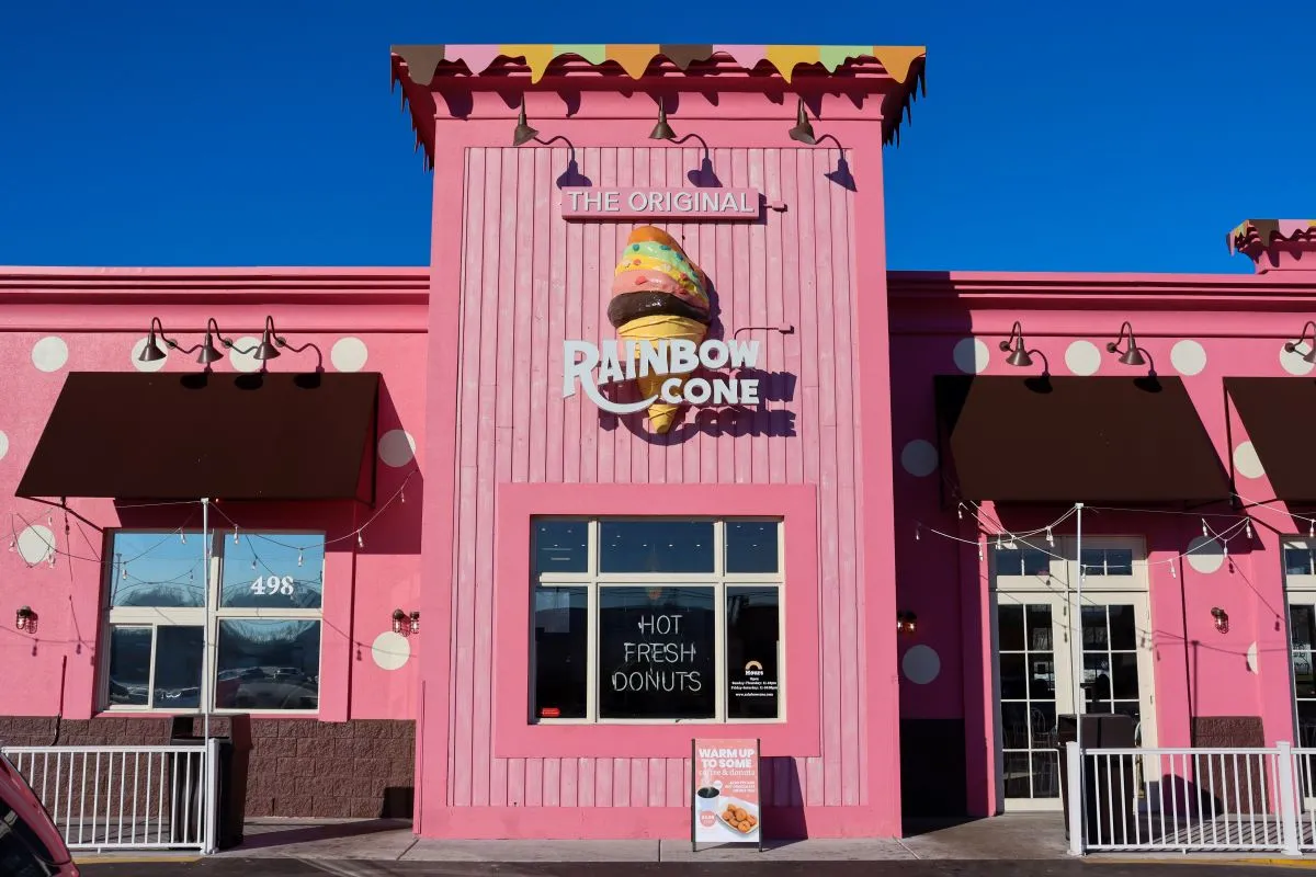 A photograph of a pink building with white polka dots with a sign that says "The Original Rainbow Cone."