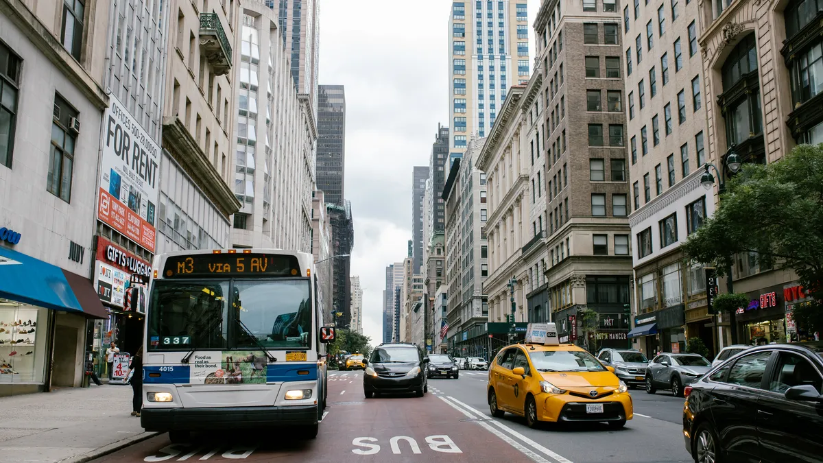 Head-on view of a transit bus in a bus only lane along a busy Manhattan avenue.