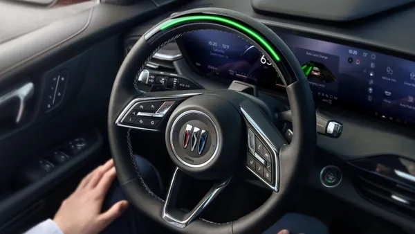 A driver using GM's Super Cruise hands-free driving systems in a Buick Envision SUV with their hands placed on their lap.