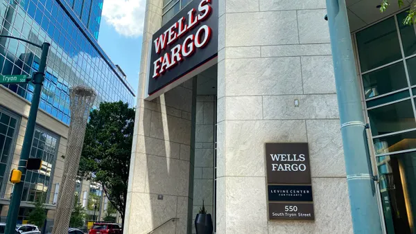 A stone building facade shows "Wells Fargo" signage above and to the side of an entrance way on a city street corner.
