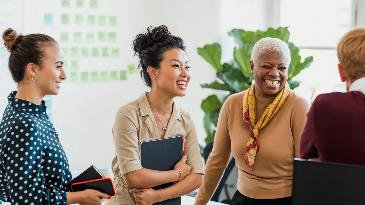 A group of coworkers stand together in the office happily