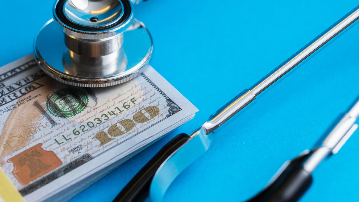 Closeup shot of a stack of one hundred dollar bills and a stethoscope.
