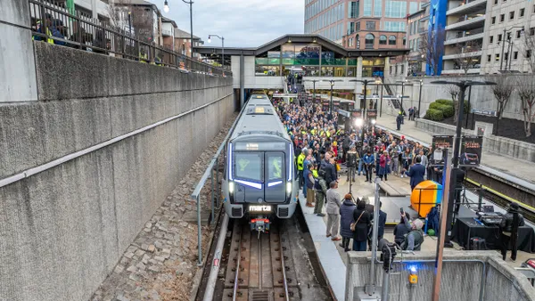 Overhead view of a modern commuter train at a station with a large crowed on the platform.